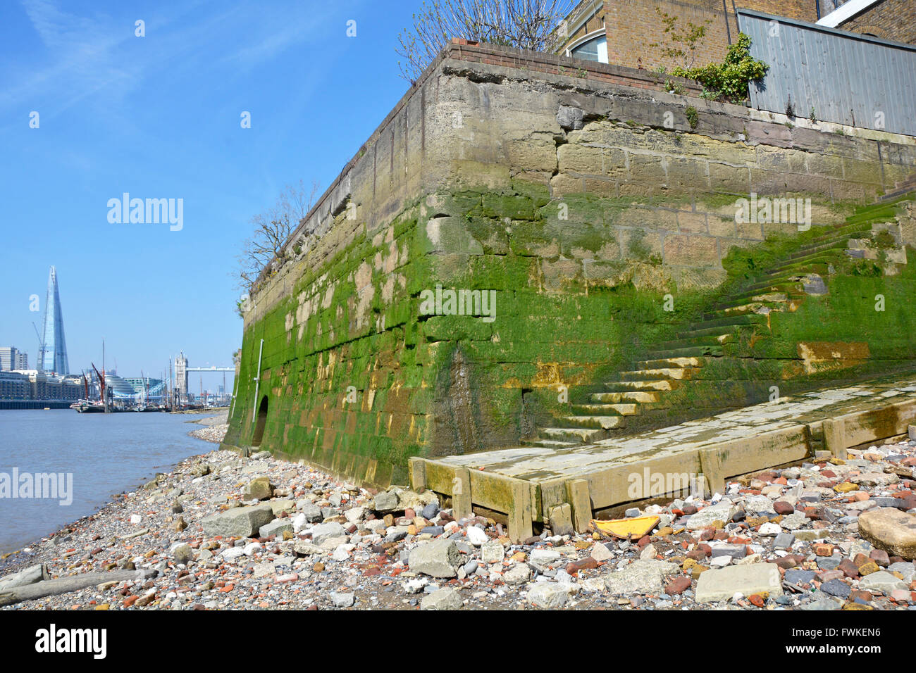 Wapping et Tamise estran à marée basse montrant ancienne base des murs des bâtiments de l'entrepôt avec le Tower Bridge et au-delà d'échardes England UK Banque D'Images