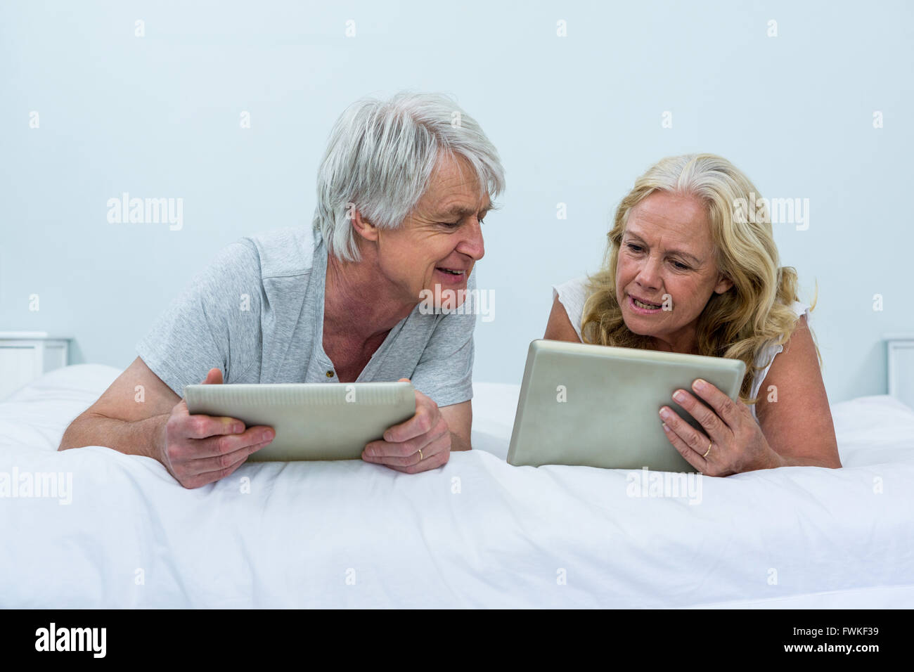 Senior couple talking lors de l'utilisation de tablettes numériques dans la chambre Banque D'Images