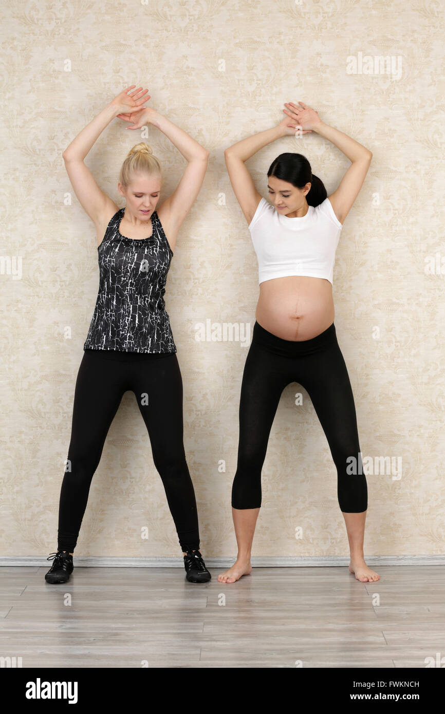 Femme enceinte faire l'exercice de remise en forme avec un entraîneur personnel Banque D'Images