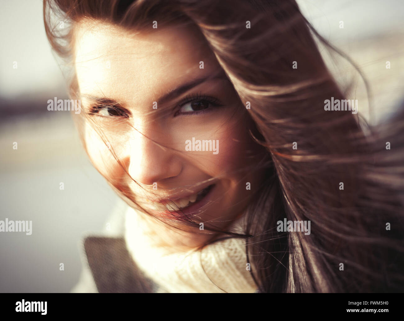 Windy portrait of attractive young woman avec un joyeux sourire à pleines dents. Le modèle montrant friendly l'expression du visage et ses cheveux est très beau Banque D'Images