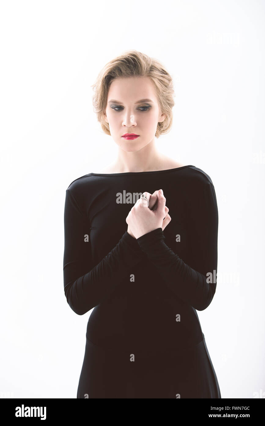 Jeune femme en robe noire sur fond blanc. Portrait permanent Banque D'Images