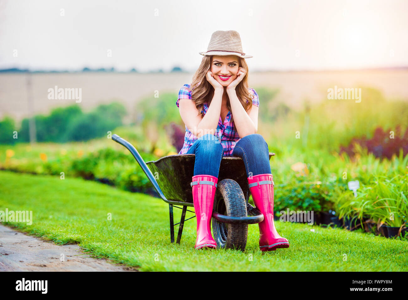 Femme assise en brouette à sunny jardin vert Banque D'Images
