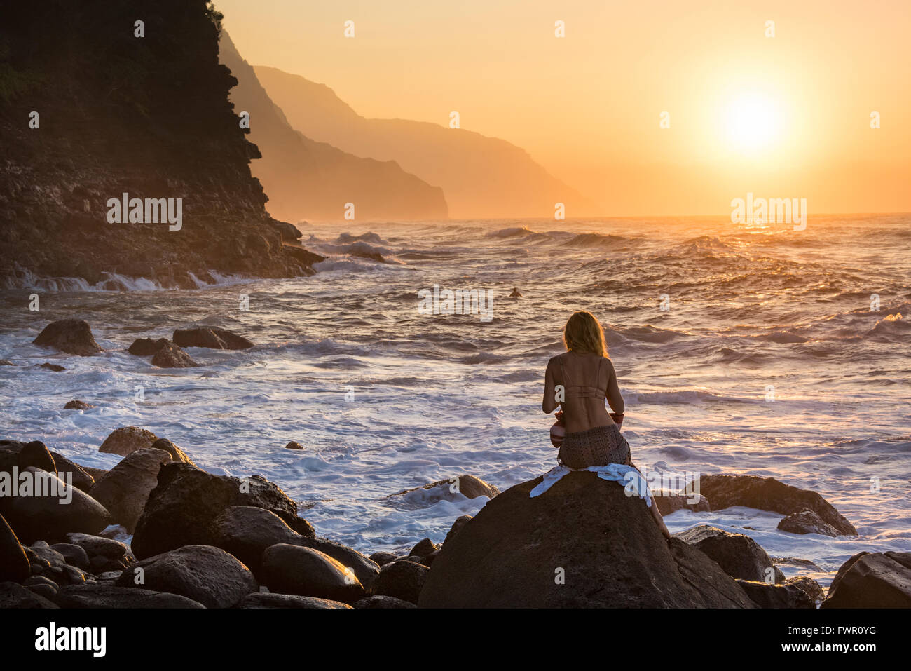 USA, Hawaii, Kauai, Haena State Park, Hanalei, Ke'e beach, femme regardant le coucher du soleil à Na Pali Coast Banque D'Images