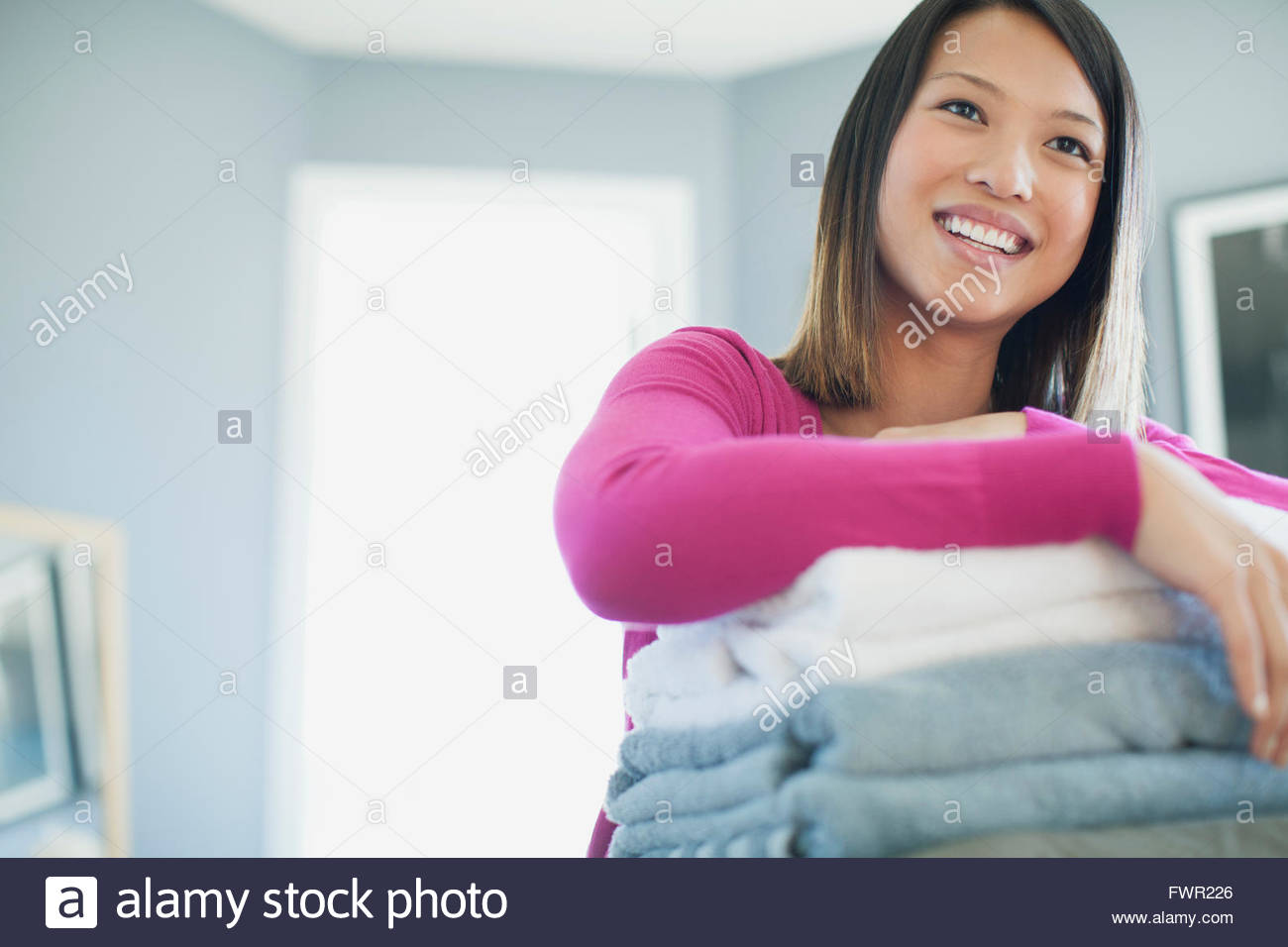 Happy woman tout en se penchant sur la pile de serviettes Banque D'Images