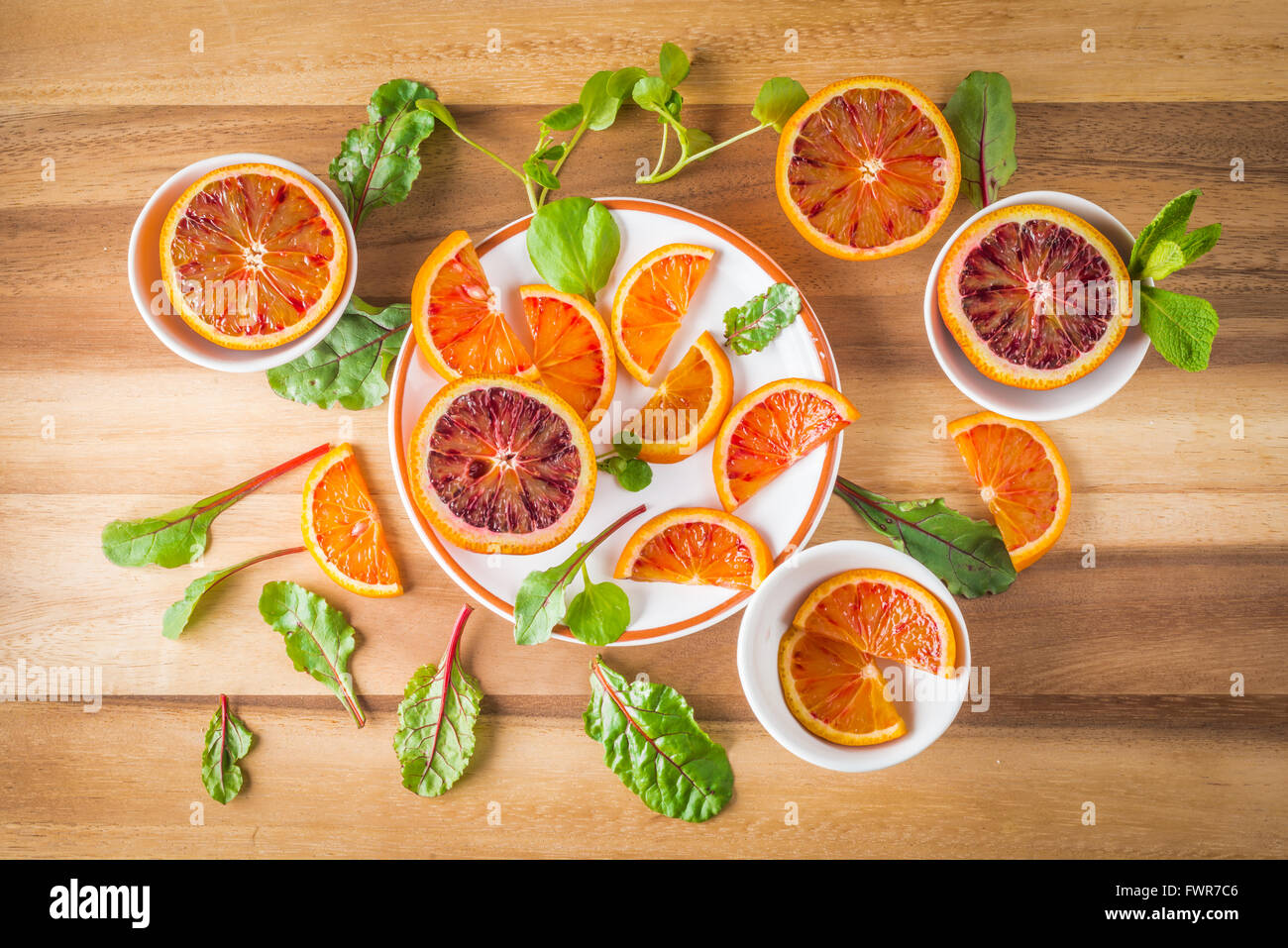 Orange sanguine sur les plaques blanches avec feuilles de salade verte sur bois, vue du dessus Banque D'Images