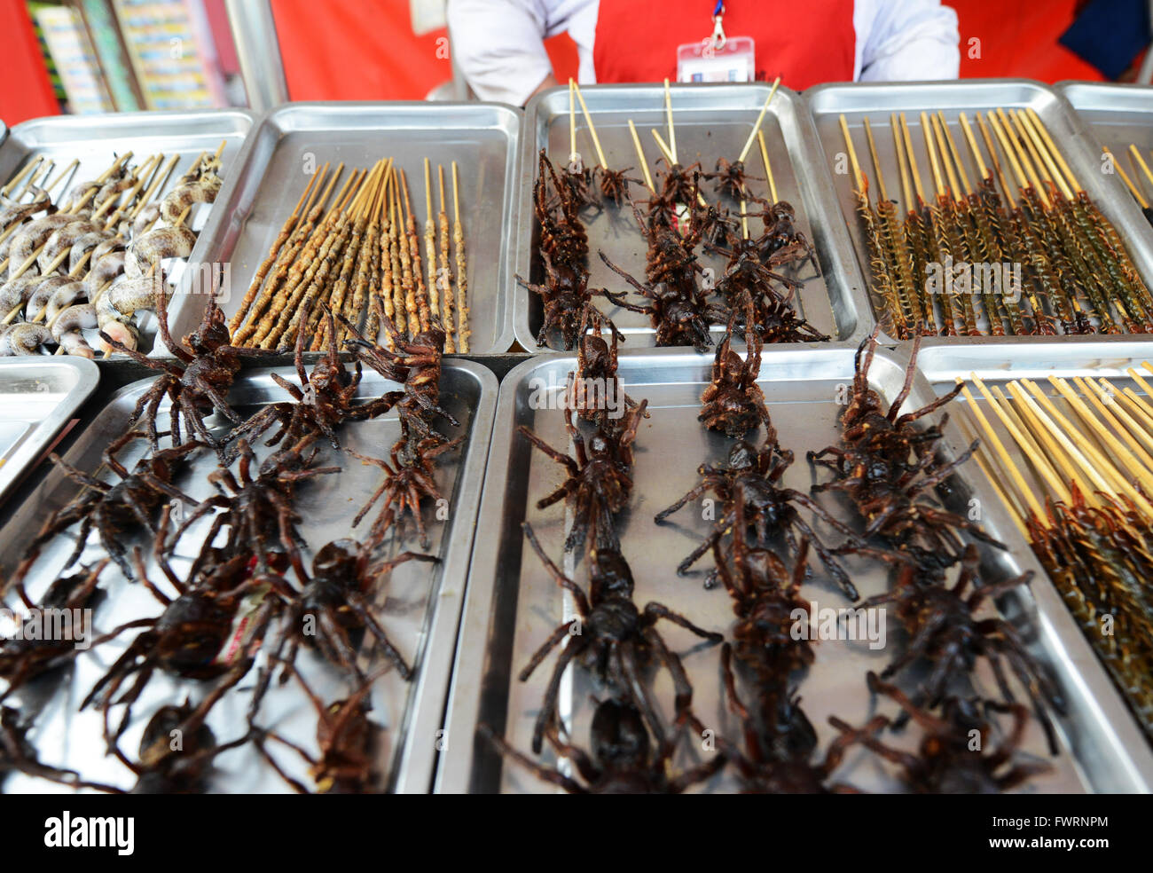 Vendeur de rue, la vente de produits alimentaires exotiques au marché alimentaire nocturne le long de la rue Wangfujing shopping district dans Beijing. Banque D'Images