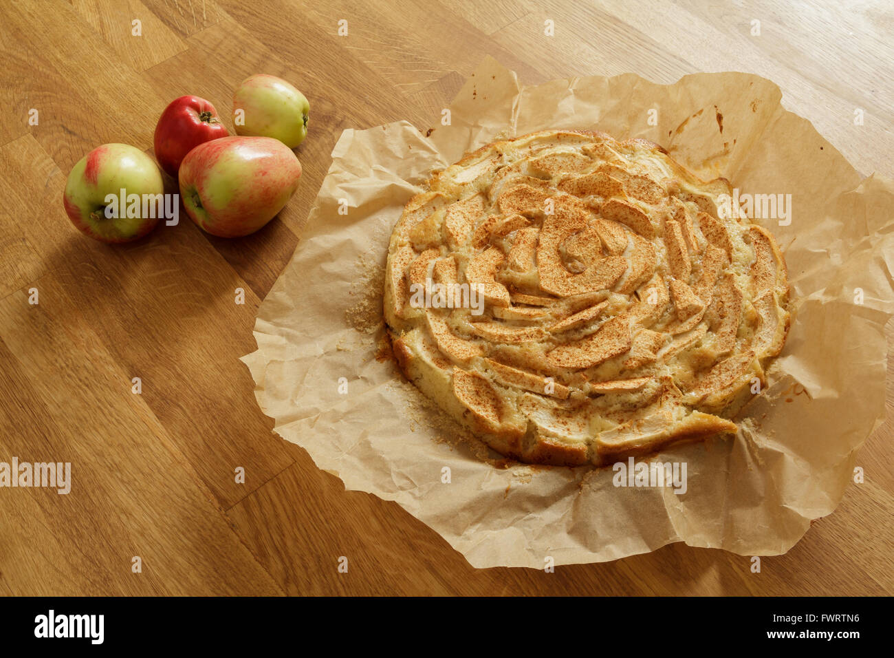 Tarte aux pommes fraîchement cuits au four sur papier cuisson avec les pommes couché à côté d'elle Banque D'Images