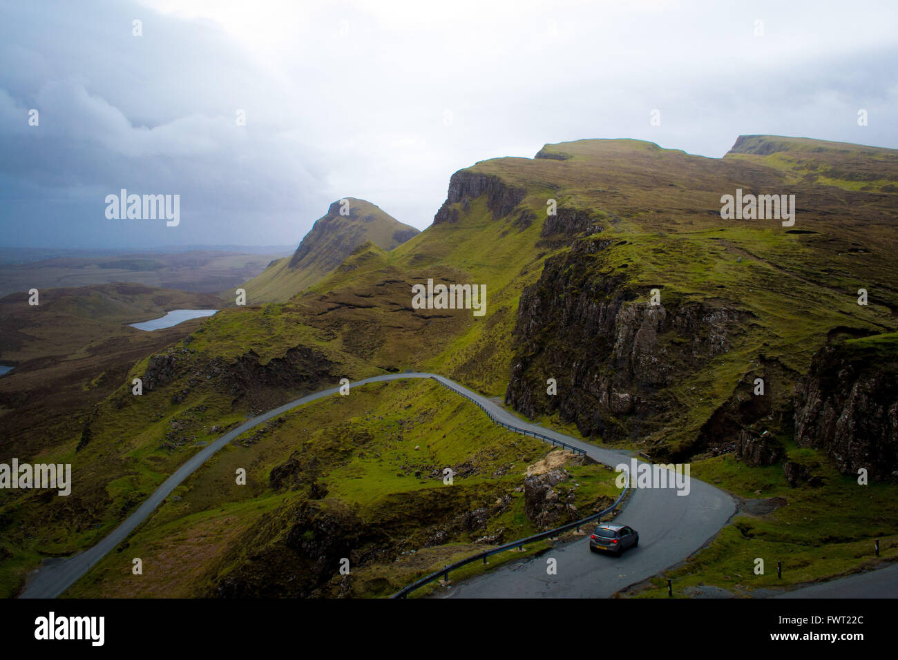 Une voiture sur la route sinueuse menant à travers la région montagneuse Quiraing sur l'île de Skye, Écosse Banque D'Images