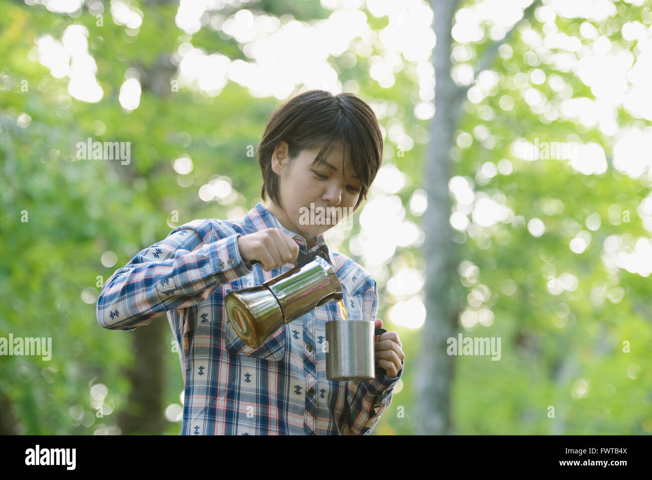 Jeune japonaise de boire du café à un camp site Banque D'Images