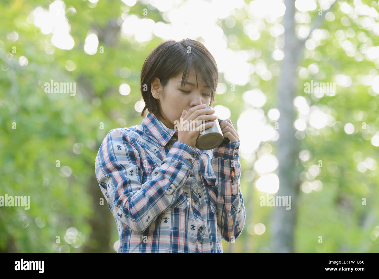 Jeune japonaise de boire du café à un camp site Banque D'Images