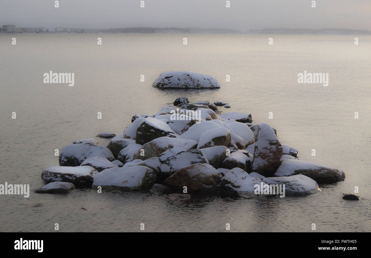 Des pierres couvertes de neige dans l'eau en hiver Banque D'Images
