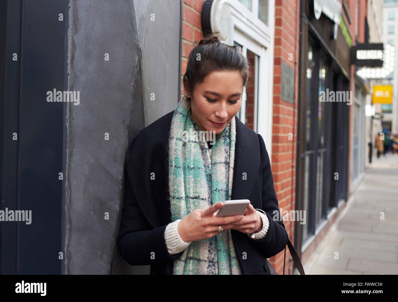 Young Woman Reading Text Messaging On City Street Banque D'Images