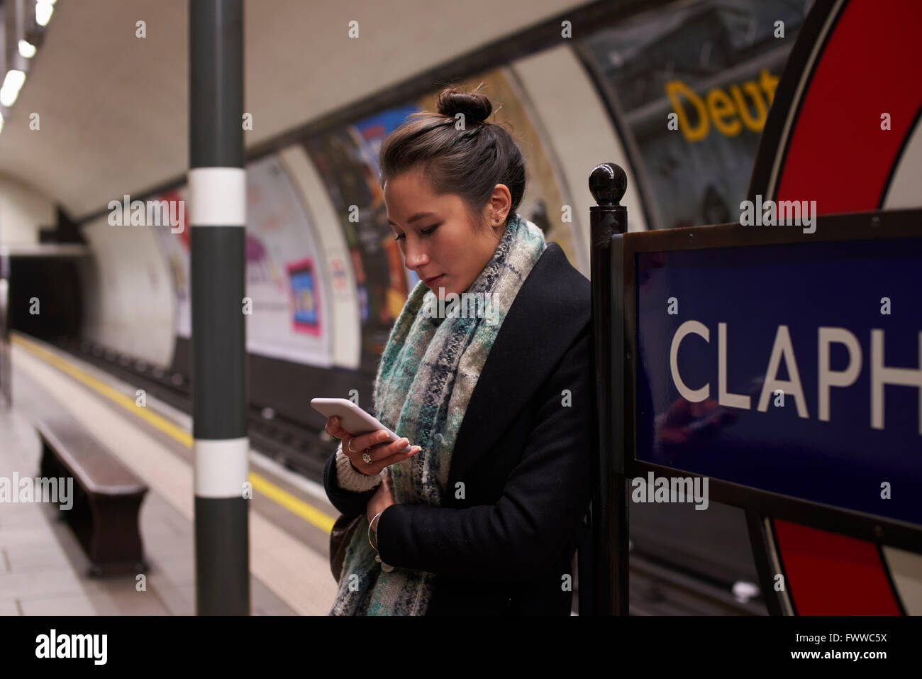 Femme Debout sur le quai de métro à au message texte Banque D'Images