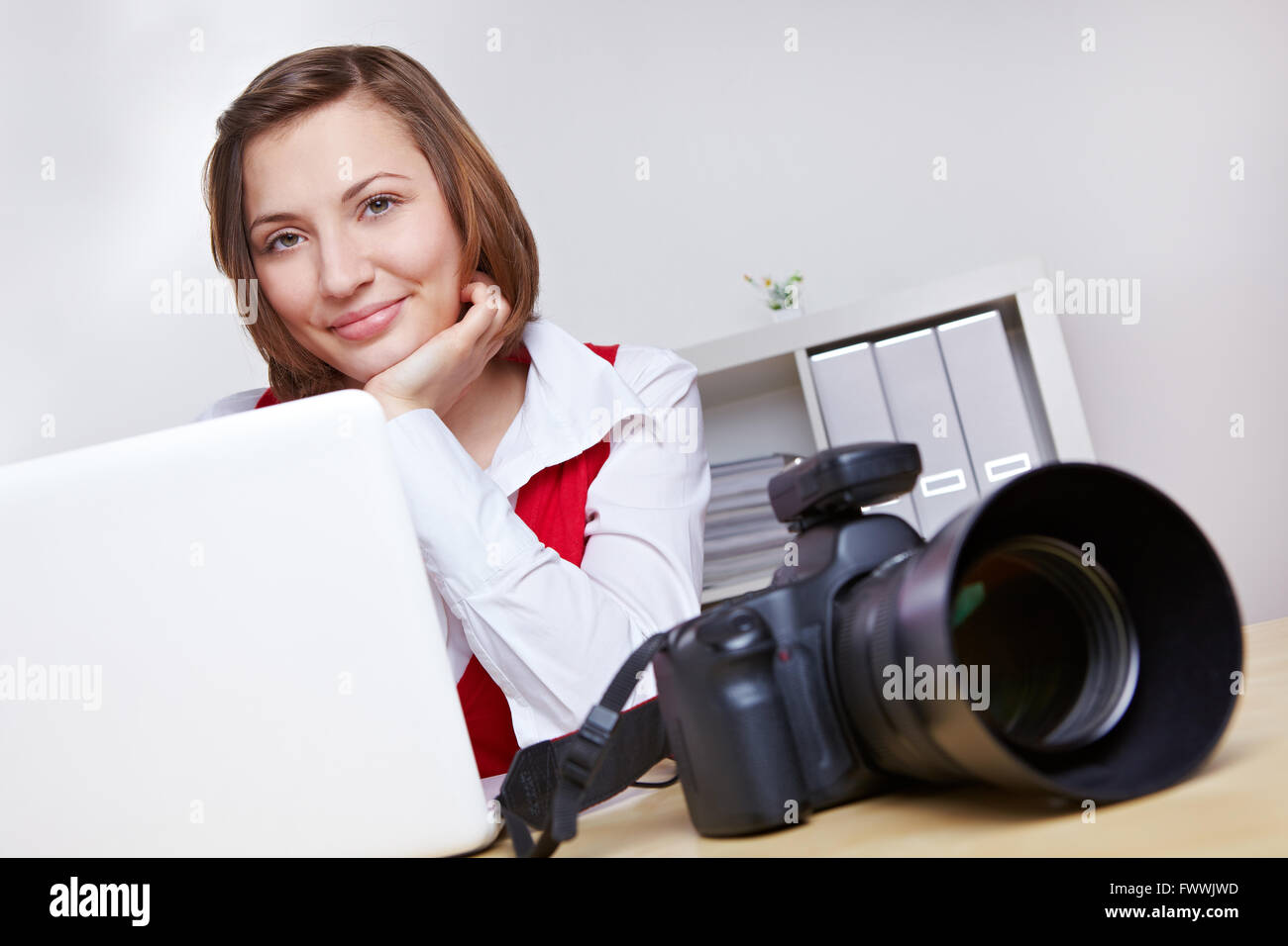 Heureux femme photographe en studio, avec un appareil et un ordinateur portable Banque D'Images