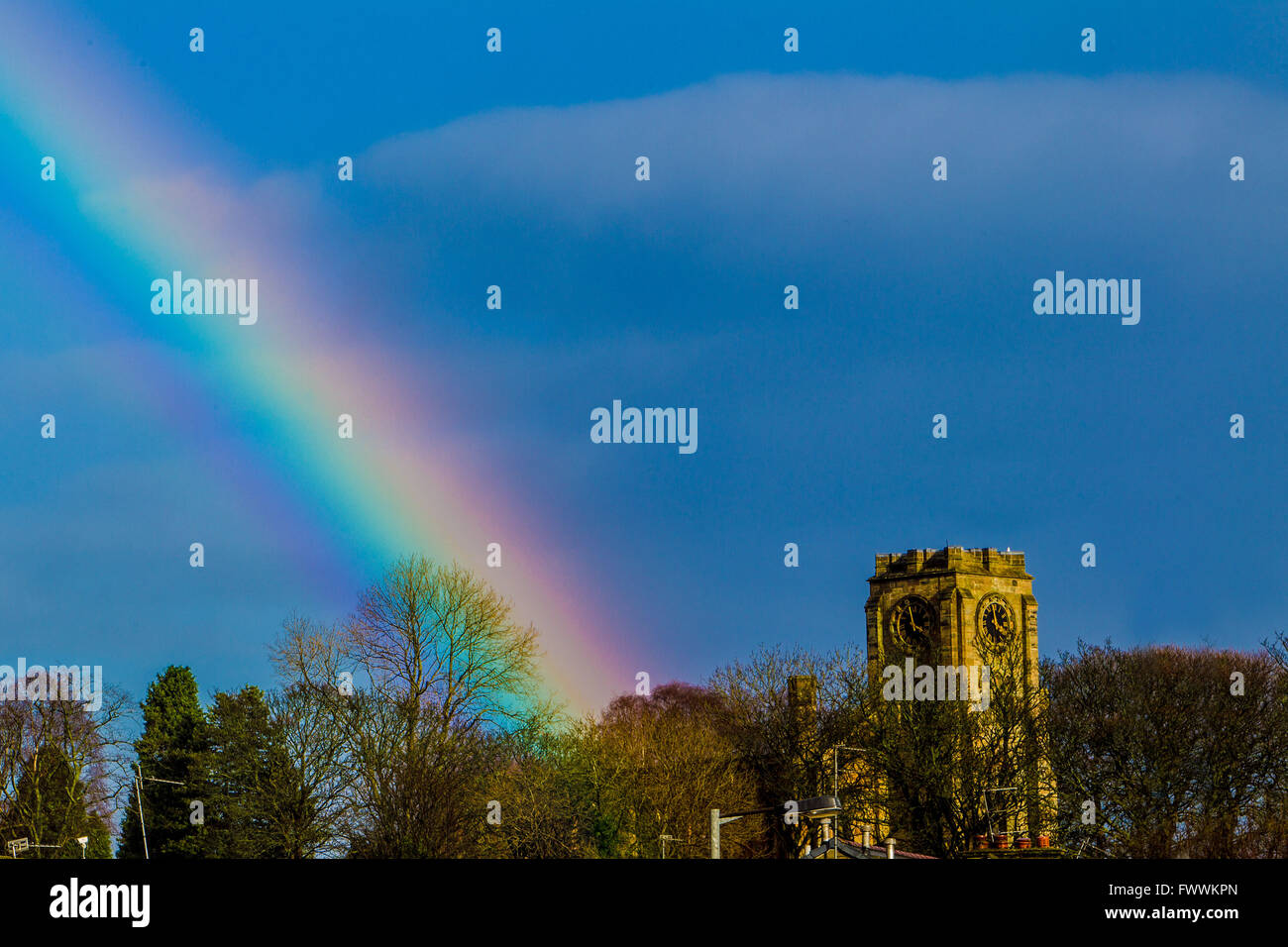 Arc-en-ciel sur village écossais de Lennoxtown montrant l'église du village et Campsies en arrière-plan Banque D'Images