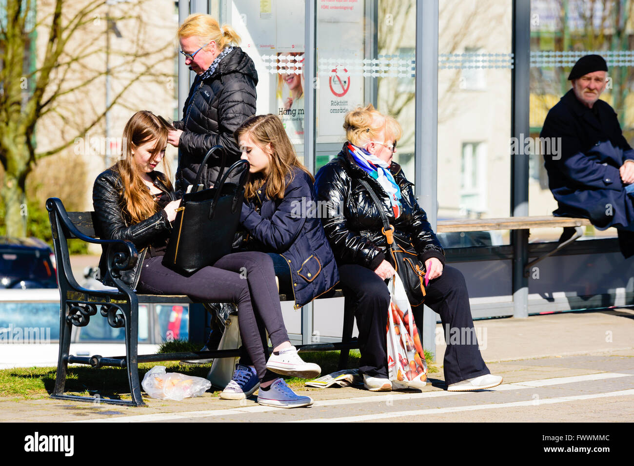 Simrishamn, Suède - 1 Avril 2016 : personnes en attente d'un bus à l'extérieur d'un abri bus. Des personnes réelles dans la vie quotidienne. Banque D'Images