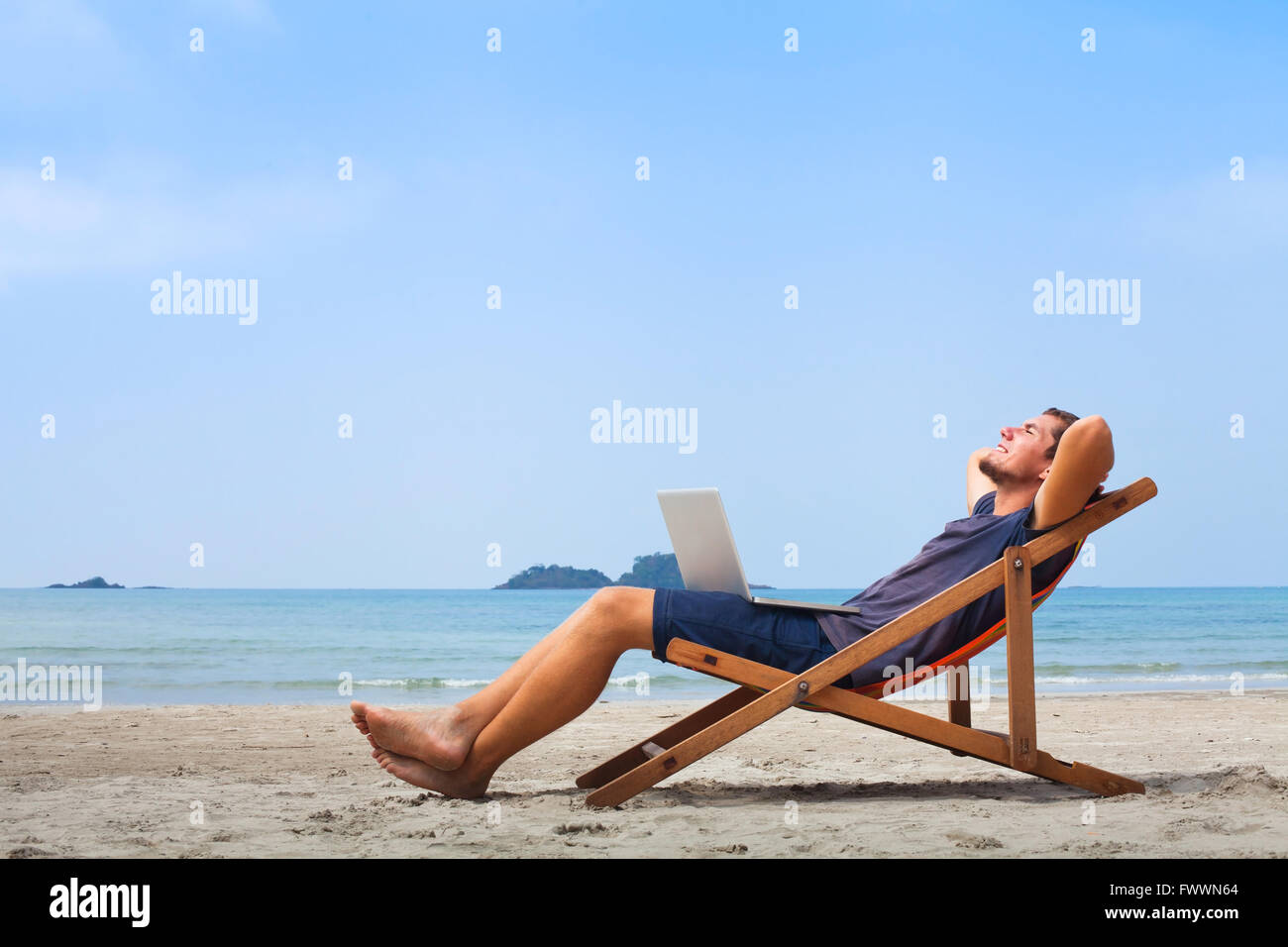 Freelancer, heureux d'affaires avec ordinateur portable sur la plage, ciel bleu Banque D'Images