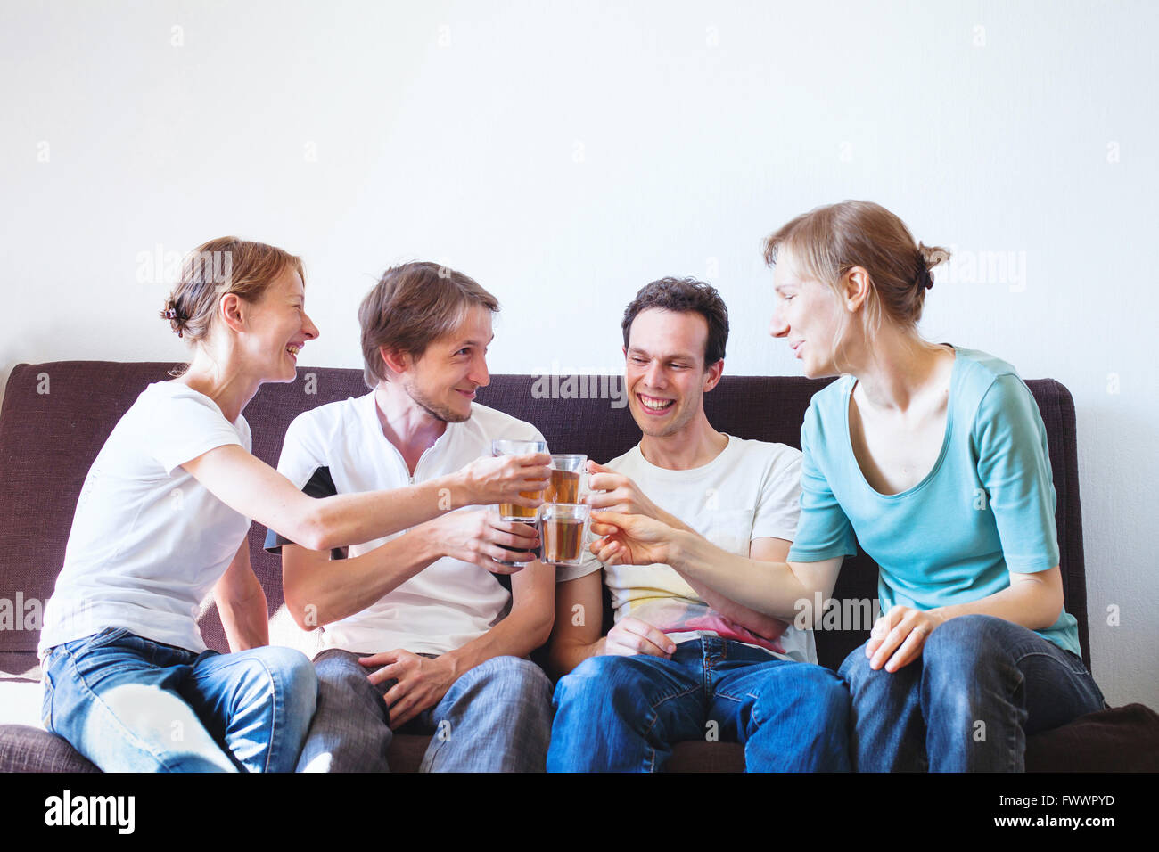 Groupe d'amis cheering at home, happy smiling people avec boissons, copyspace Banque D'Images