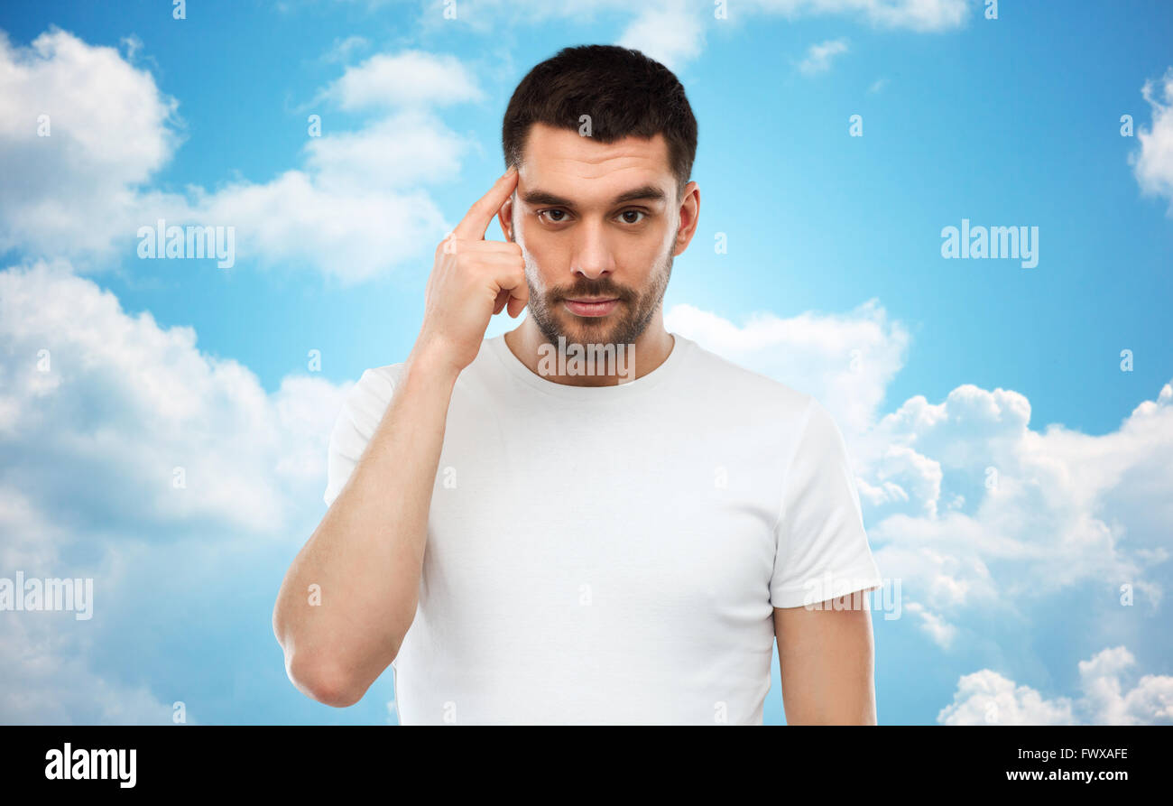 L'homme avec le doigt à temple sur fond de ciel bleu Banque D'Images