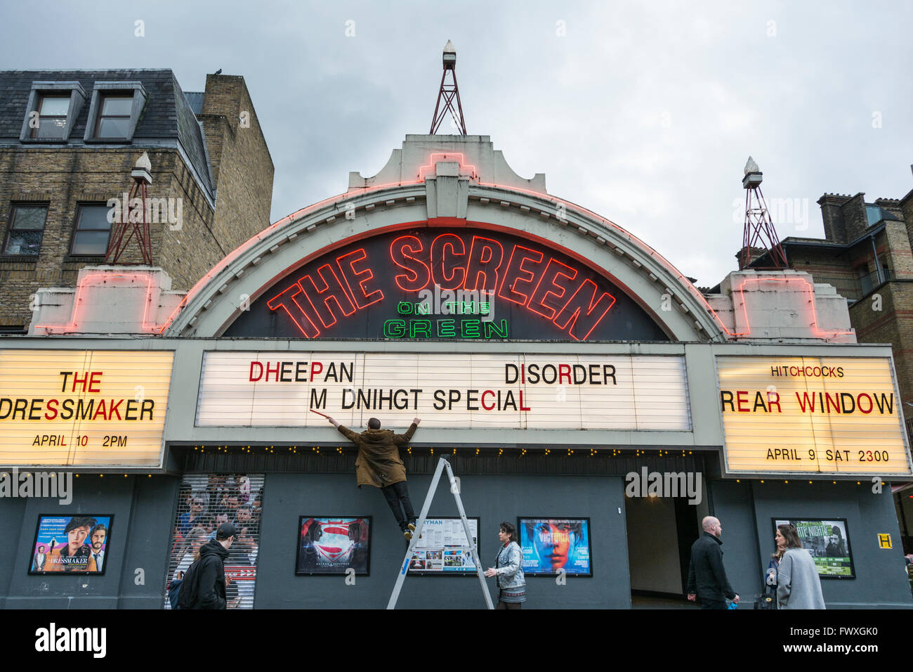 Un homme corrige l'orthographe à l'avant de l'écran sur le Livre vert sur le cinéma Street, Islington, Londres, Royaume-Uni Banque D'Images