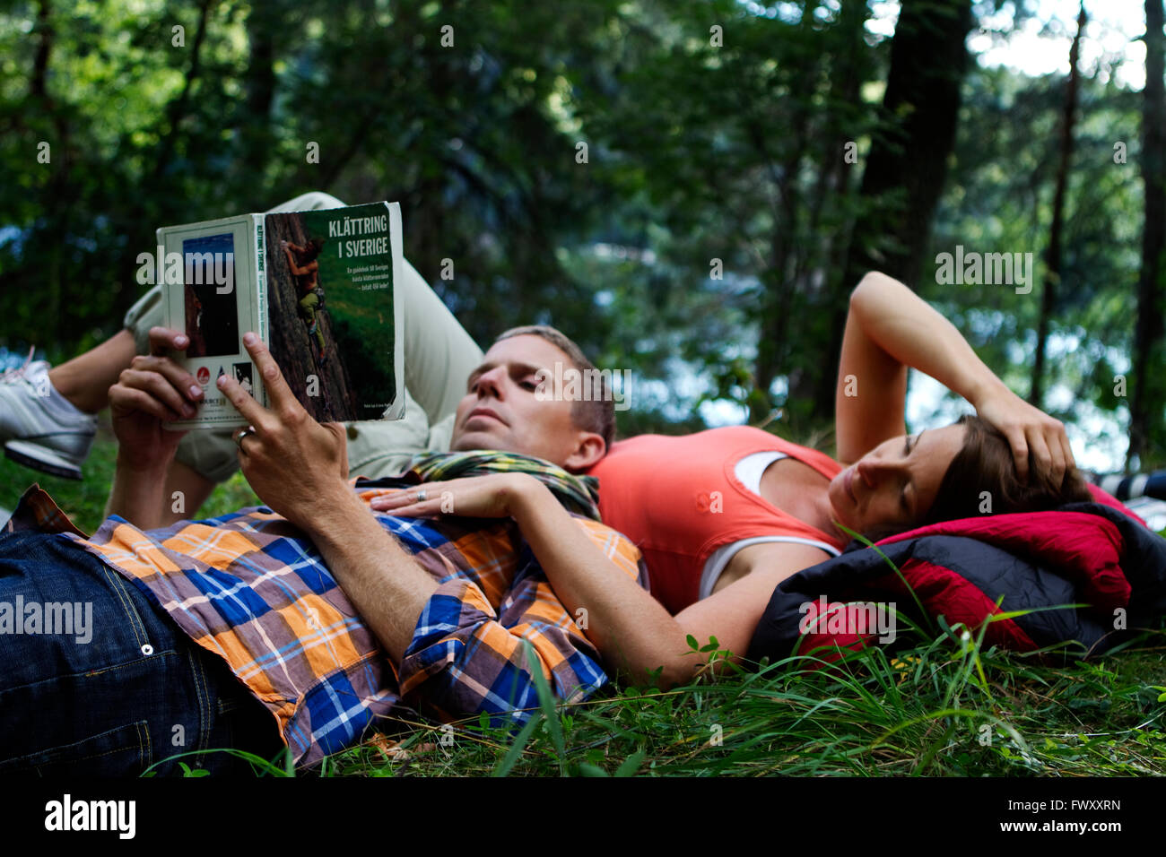 La Suède, l'océan, Agelsjon les randonneurs, allongé sur l'herbe et lecture guidebook Banque D'Images