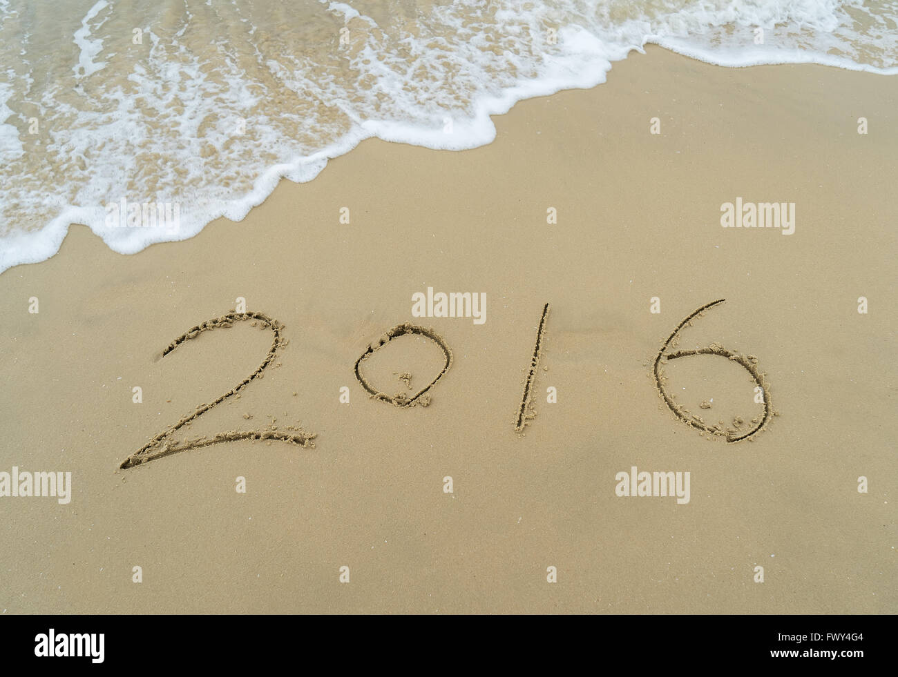 Année 2016 écrit à la main sur le sable blanc en face de la mer Banque D'Images
