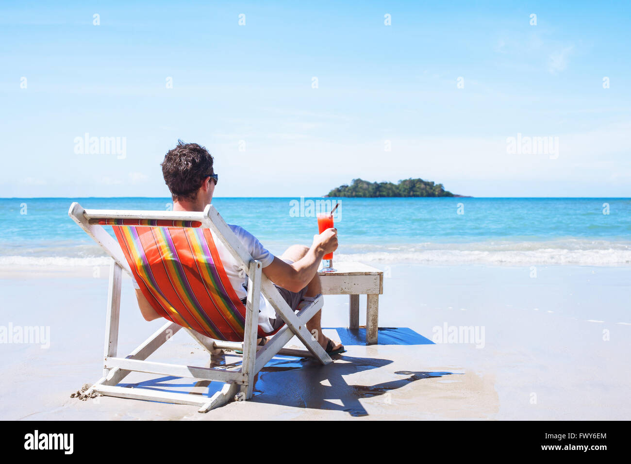 L'homme se détendre sur une plage privée sur Paradise Island, vacances de luxe, avec cocktail assis près de la mer Banque D'Images