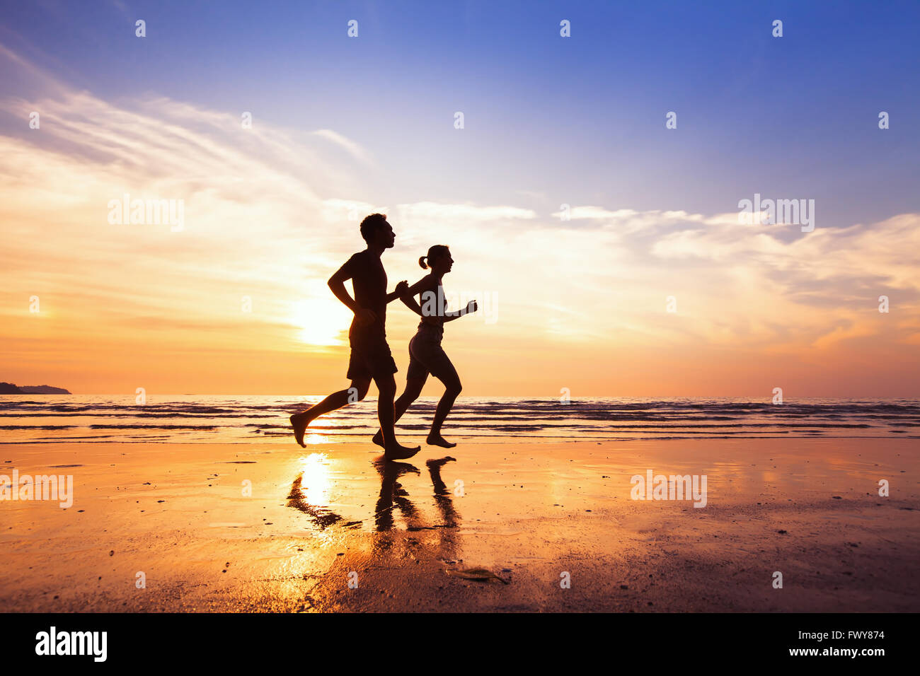 Sport et mode de vie sain, deux personnes courir au coucher du soleil sur la plage Banque D'Images