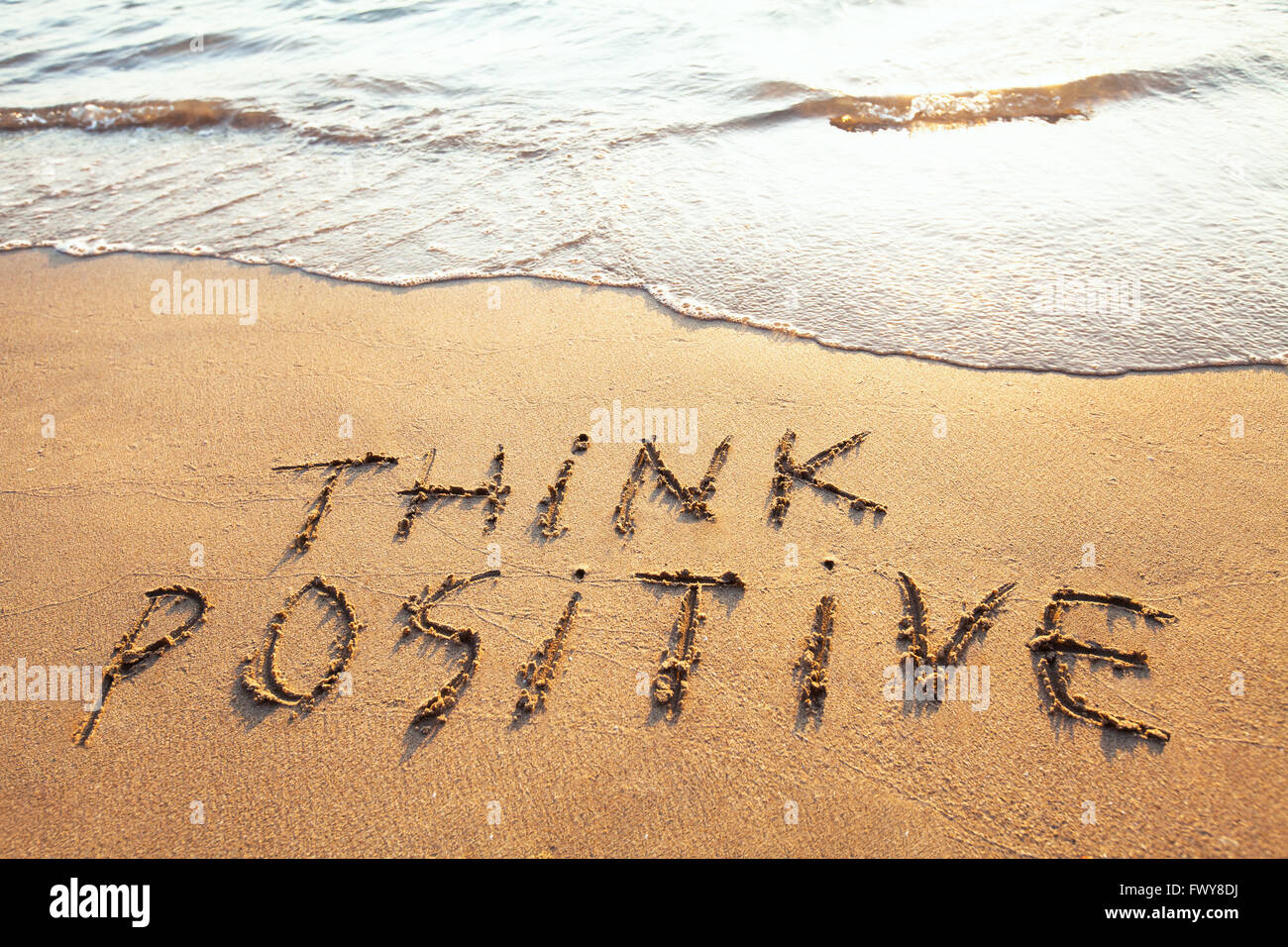 Pensez positif, concept written sur le sable Banque D'Images