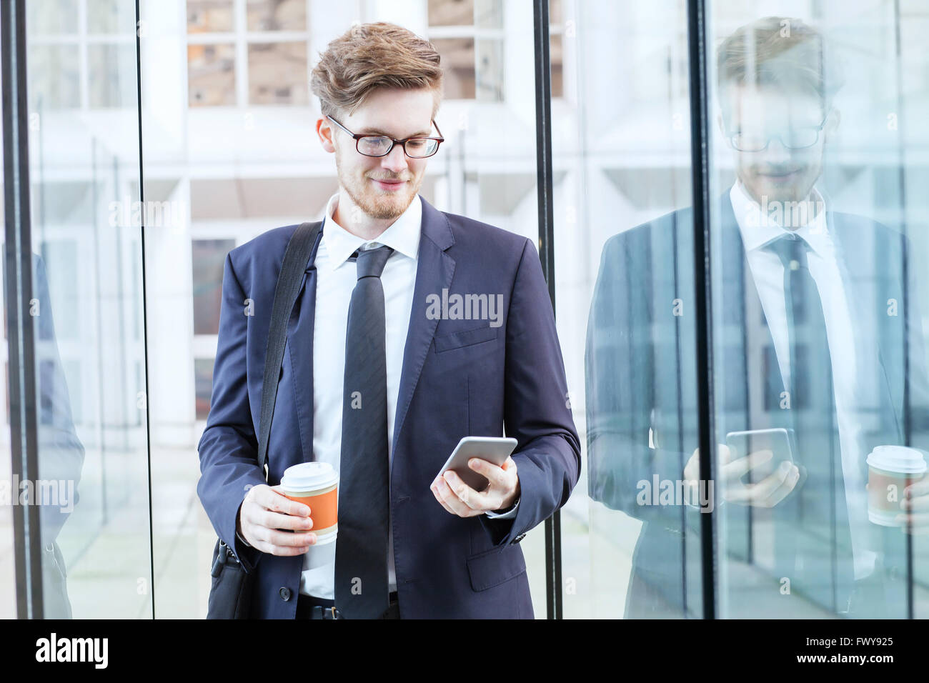 Young businessman walking dans l'aéroport et la vérification du courrier électronique sur le smartphone. Banque D'Images