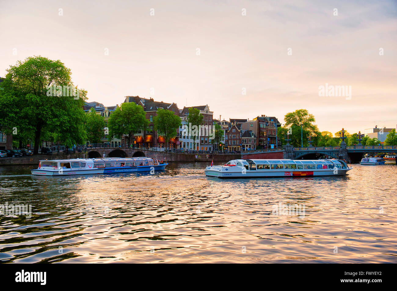 Amsterdam, Pays-Bas. Un bateau couvert de croisière au coucher du soleil pour les touristes sur les beaux canaux de la Binnen de la rivière Amstel Banque D'Images