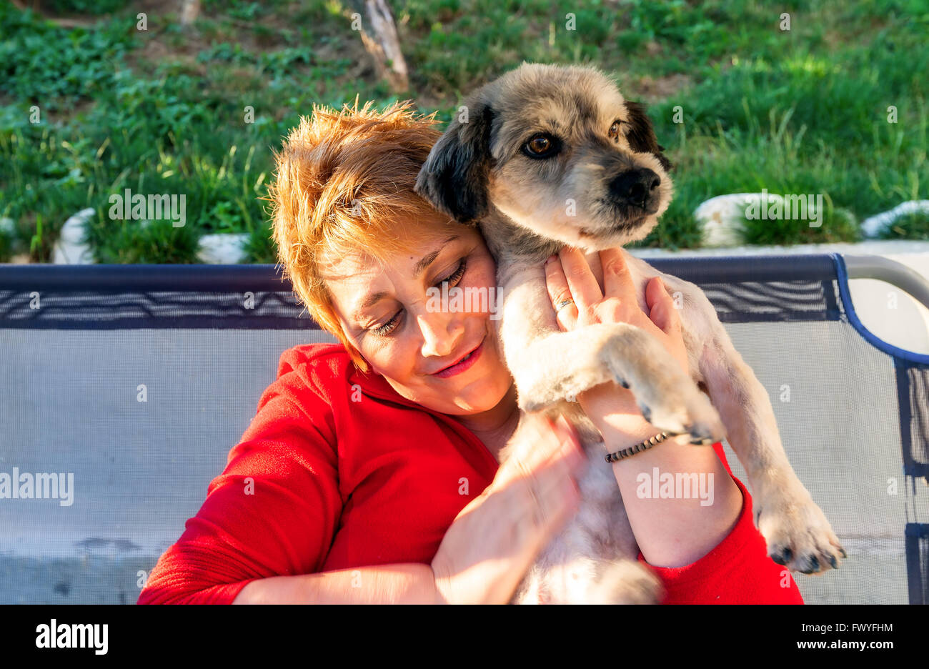 Hunedoara, Roumanie - 01 juillet 2014 : Happy Blonde Woman embrayer sur la poitrine en Hunedoara chien nouvellement adoptée le 1 juillet 2014 Banque D'Images