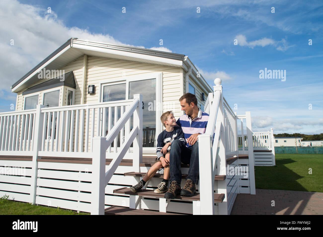 Père et fils à la caravane statique blanc sur bleu ciel journée ensoleillée Banque D'Images