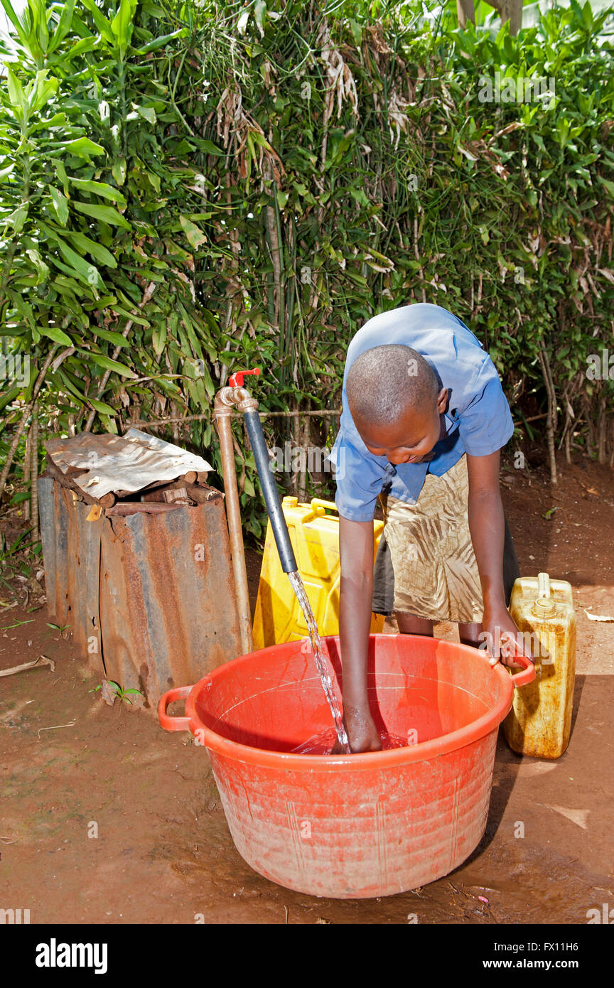 Femme rwandaise de remplir le récipient avec de l'eau douce à partir d'un robinet. Banque D'Images