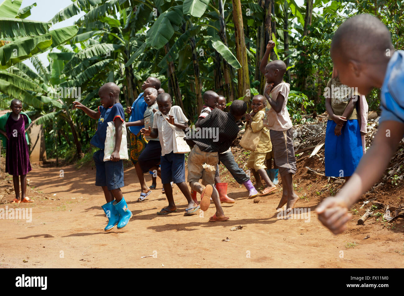 Groupe d'enfants rwandais jouant un jeu de ballon sur une route poussiéreuse et d'avoir du plaisir. Banque D'Images