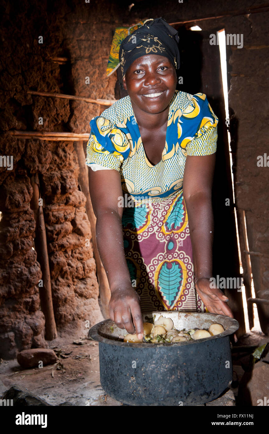 Femme préparant un repas de pommes de terre, les haricots et les herbes dans un bol. Le Rwanda. Banque D'Images