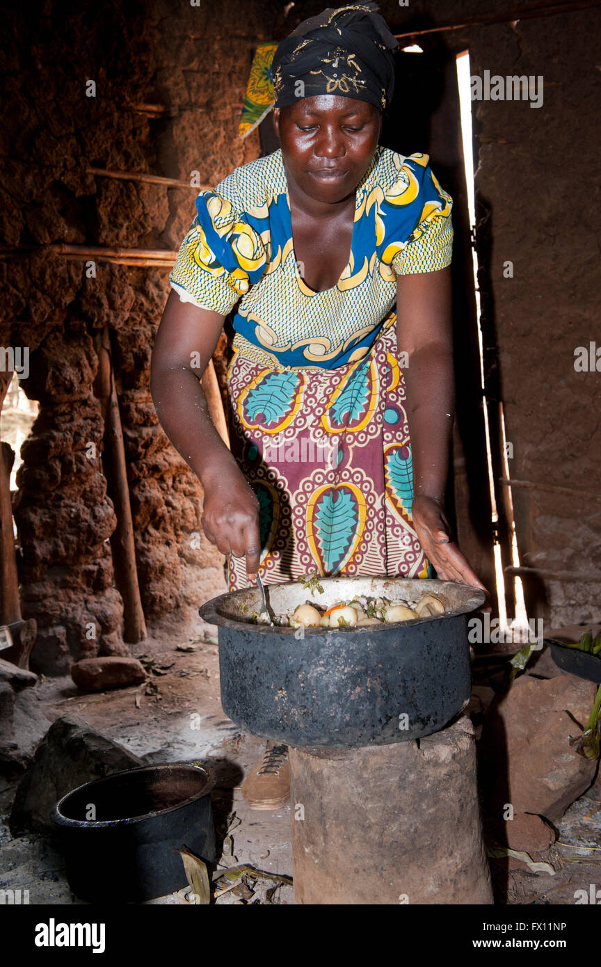 Femme préparant un repas de pommes de terre, les haricots et les herbes dans un bol. Le Rwanda. Banque D'Images