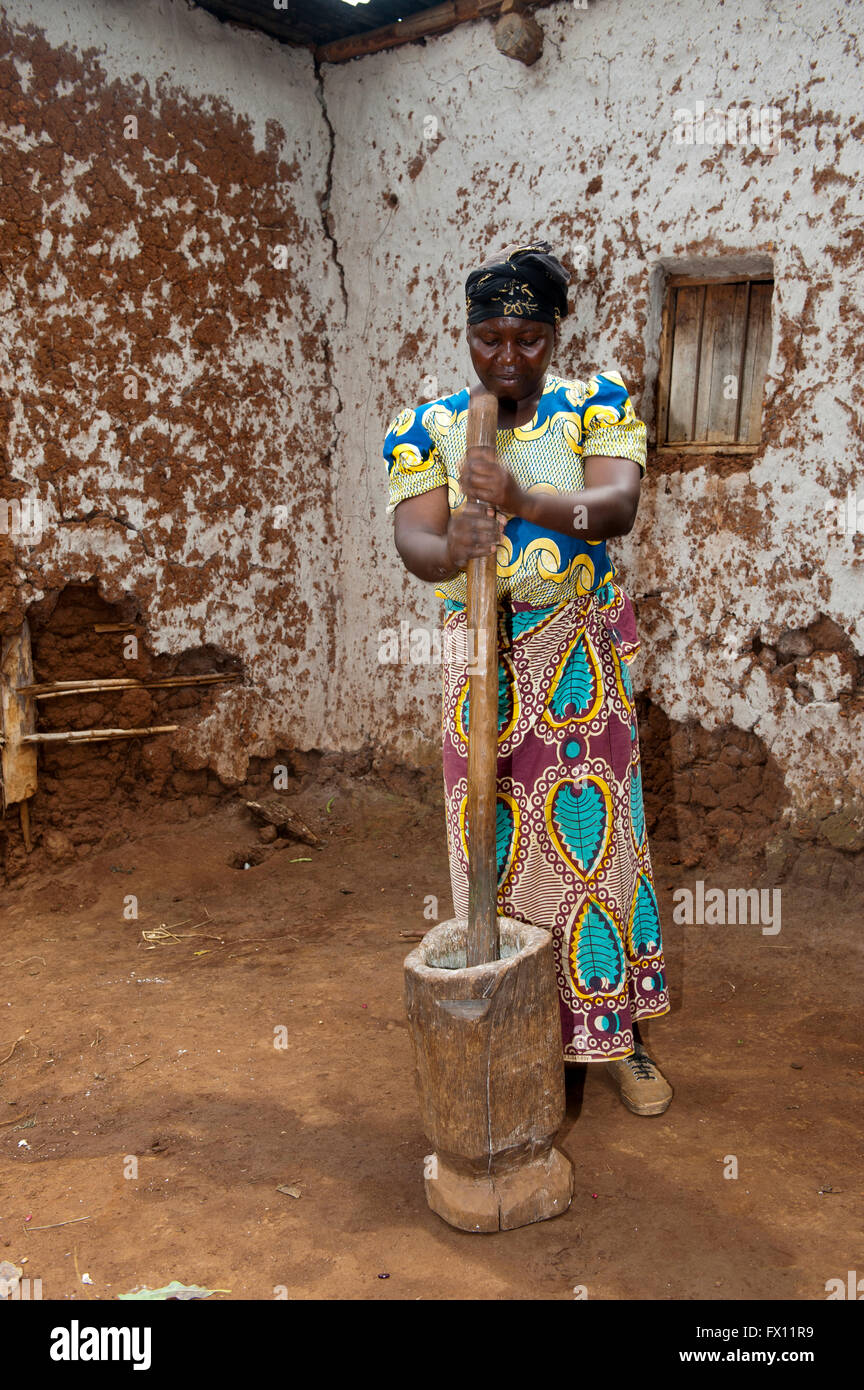 Femme avec un post de manioc de meulage et de pot pour créer de farine de manioc à être utilisés en pâtisserie. Le Rwanda. Banque D'Images