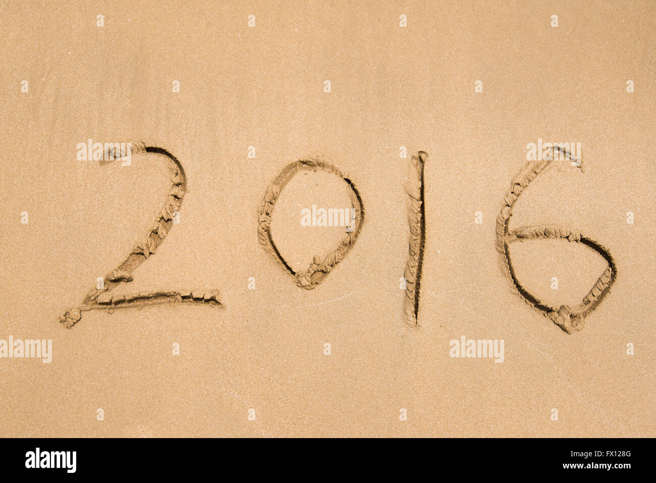 Année 2016 écrit à la main sur le sable blanc en face de la mer Banque D'Images