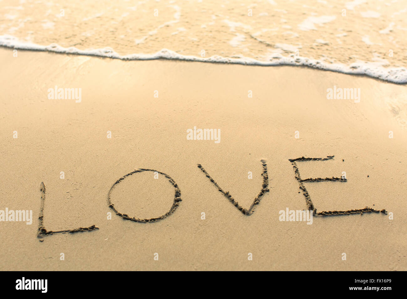 Amour - écrites manuellement sur la texture du sable de la mer. Banque D'Images