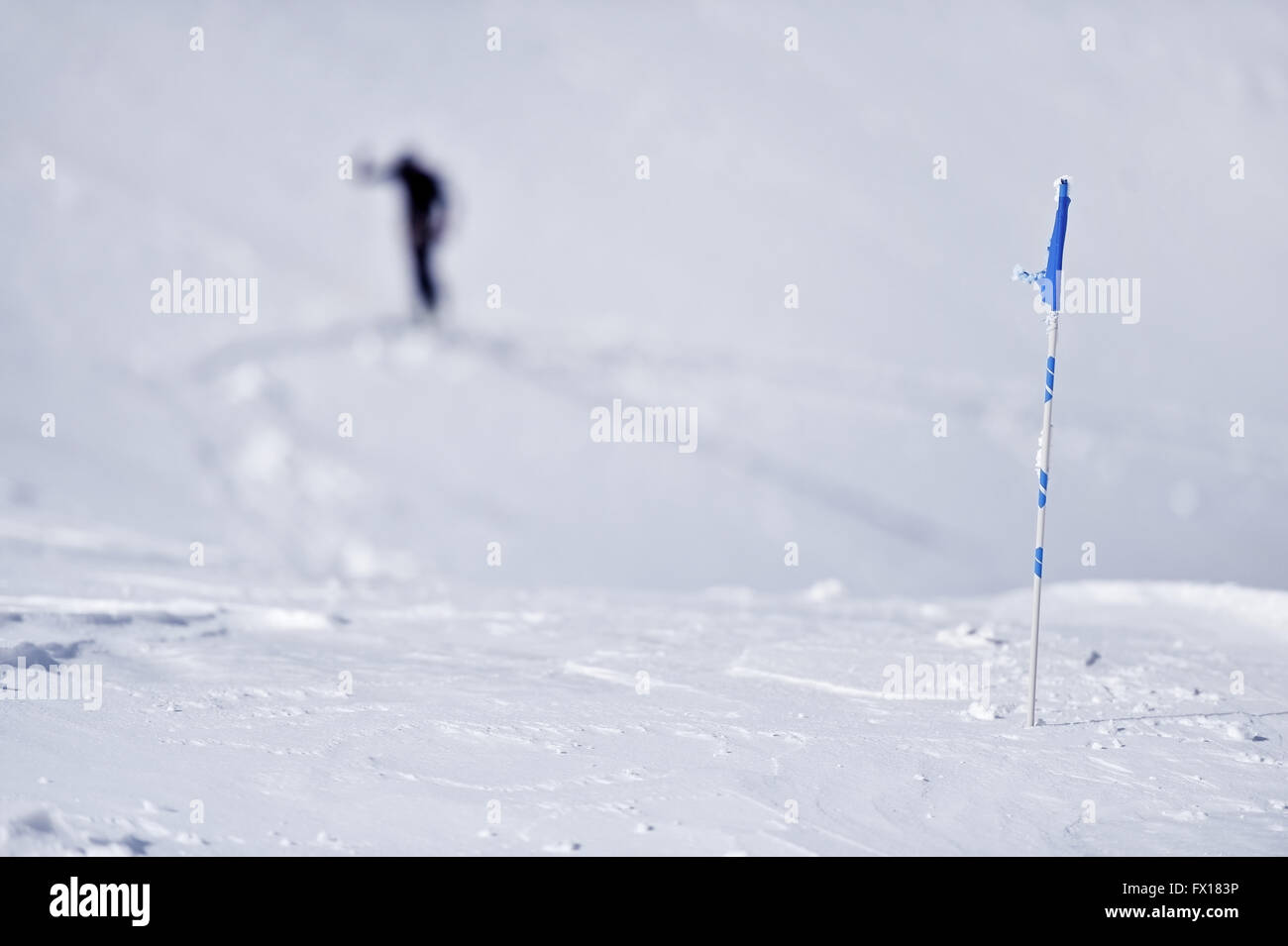 Drapeau bleu soufflé par le vent sur une montagne en hiver et skieur en arrière-plan Banque D'Images