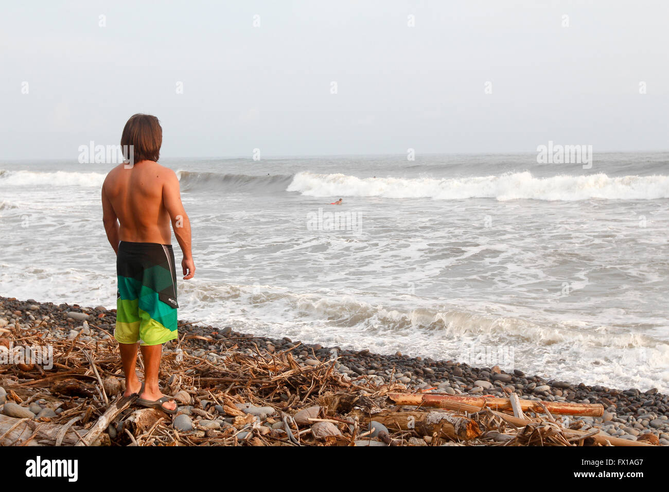 Surfeur sur la plage studies la houle. Photographié à El Tunco beach, El Salvador, Banque D'Images