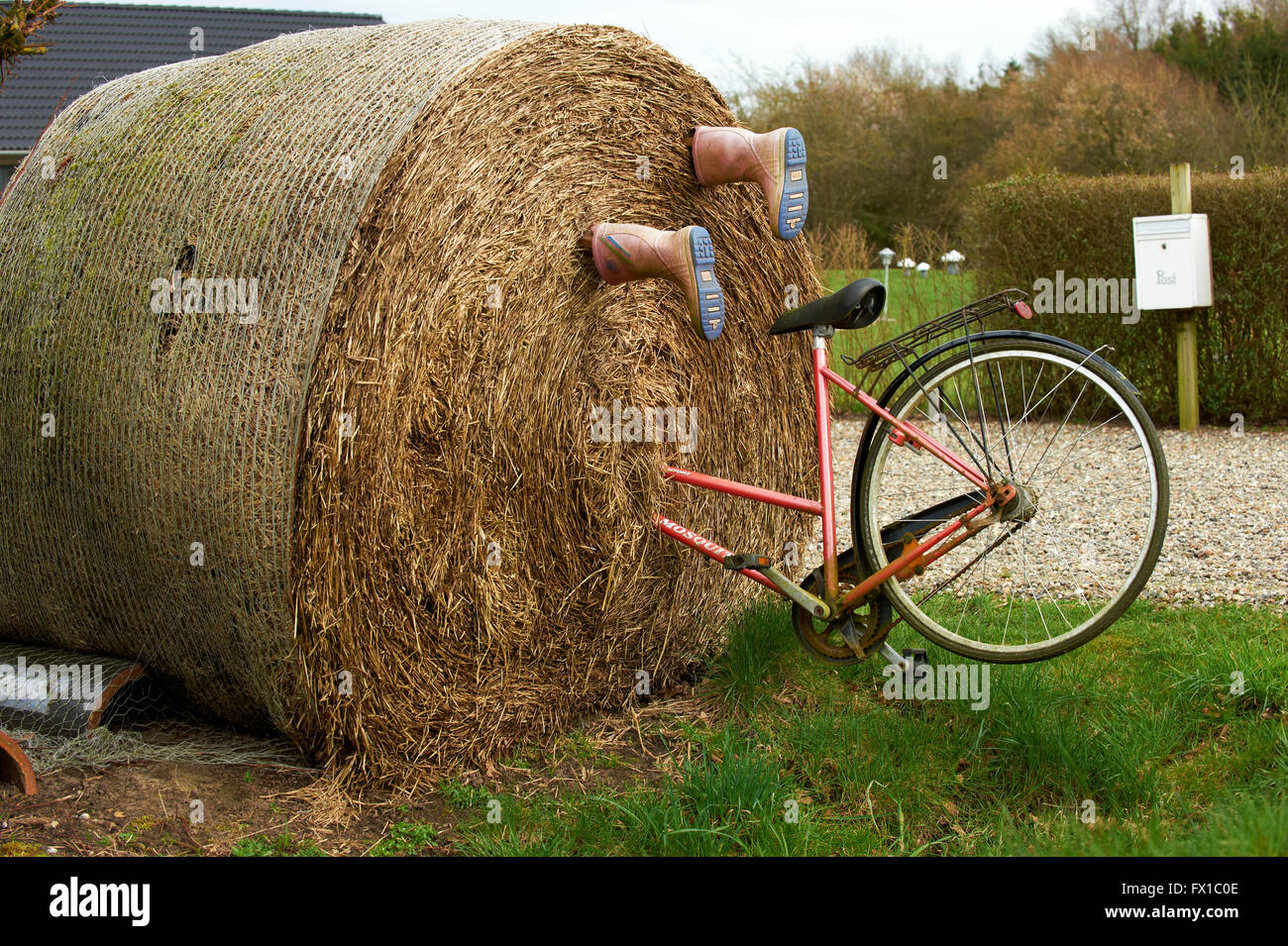 Grosse botte de paille avec location et des bottes en caoutchouc monté à regarder comme si la personne qu'elle a disparu dans la balle Banque D'Images