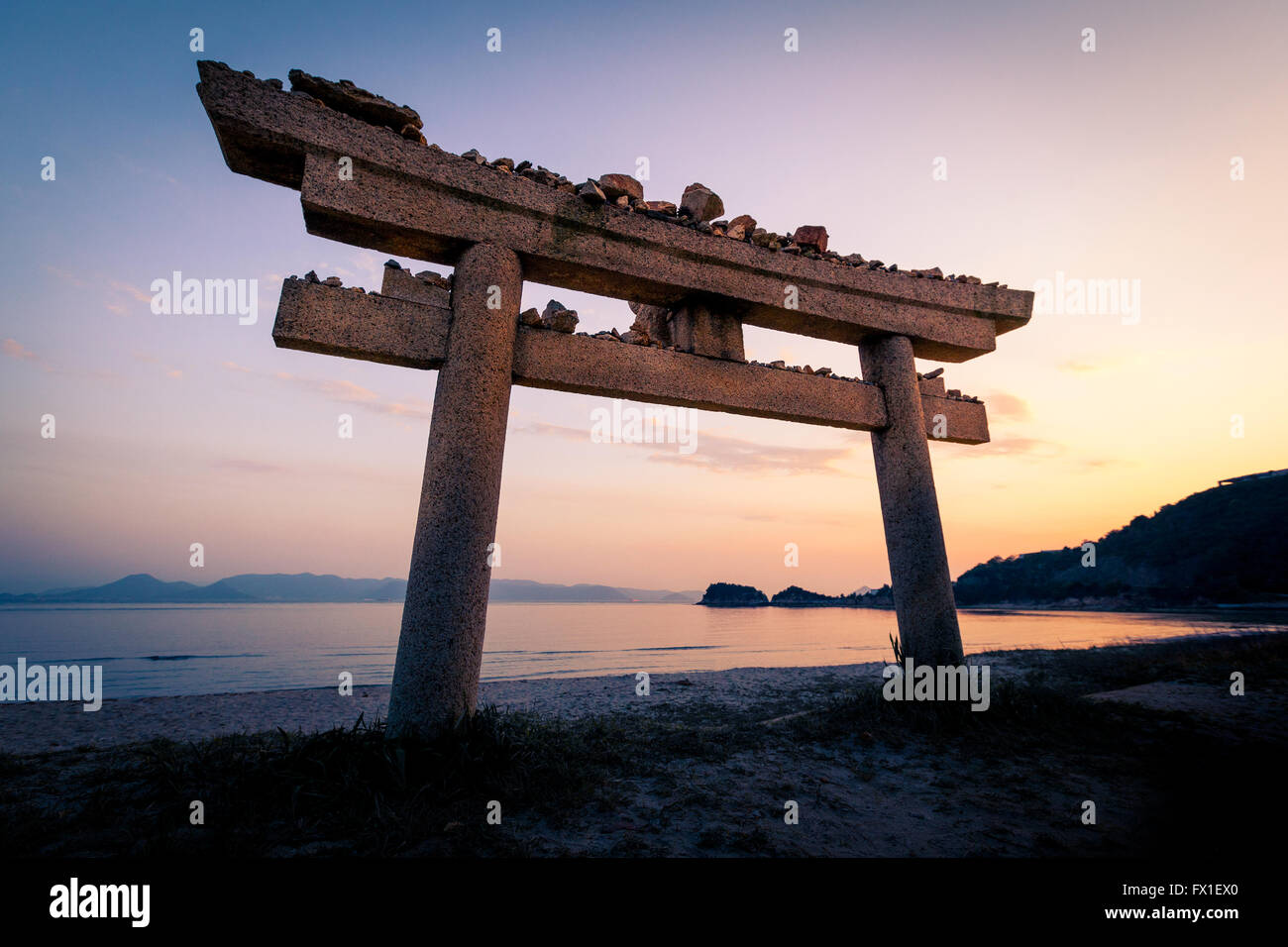 Torii de pierre sur la plage sur l'île de Naoshima, au Japon au coucher du soleil Banque D'Images