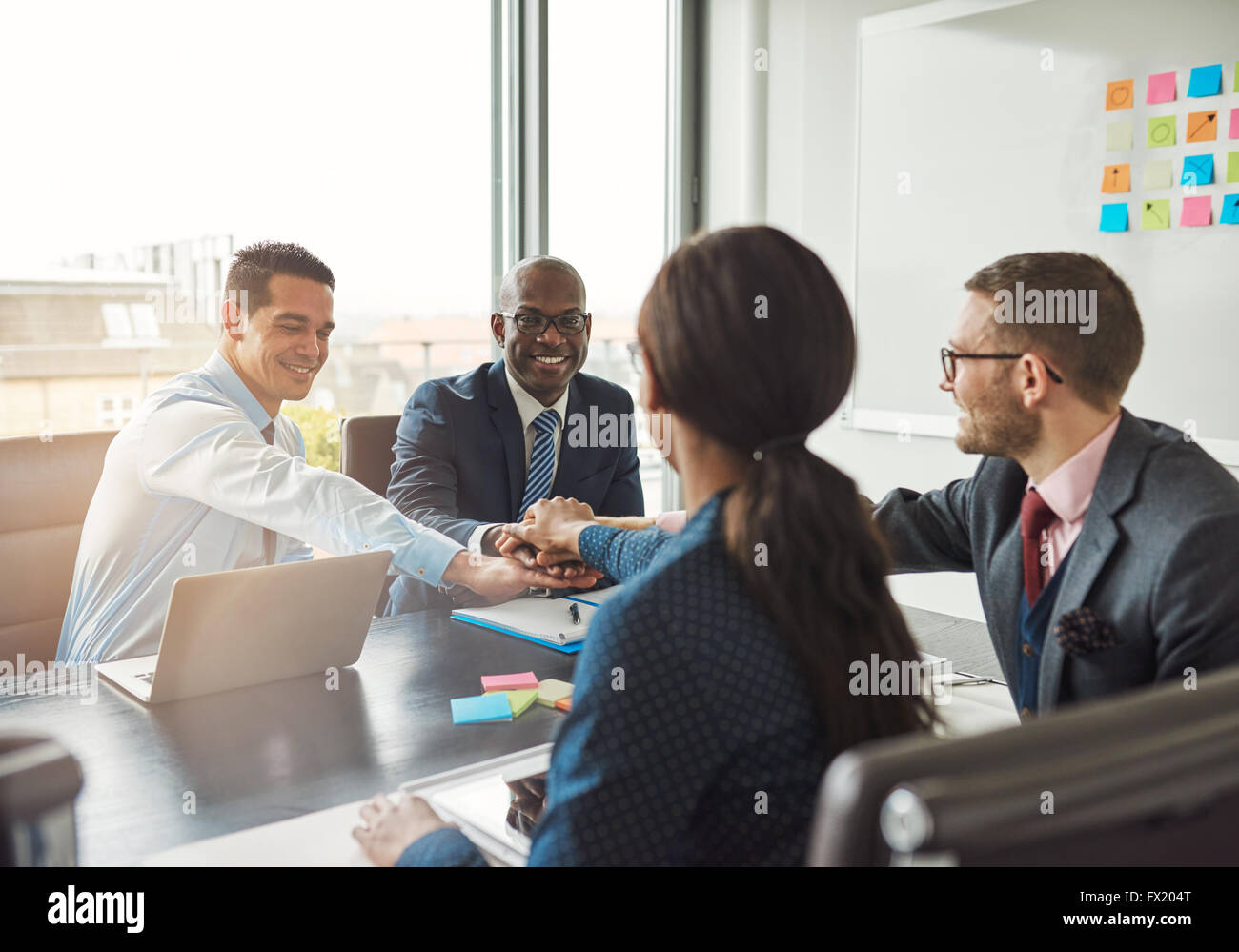 L'équipe entreprise multiraciale réussie travailler ensemble affirment leur engagement en liant les mains autour d'une table de bureau lors d'une m Banque D'Images