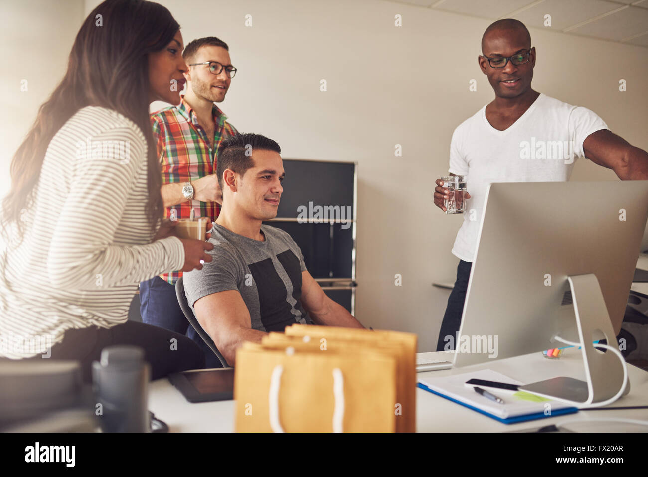 Groupe diversifié d'hommes et de femmes entrepreneurs adultes rassemblés autour de grand écran d'ordinateur sur le bureau pour réunion Banque D'Images