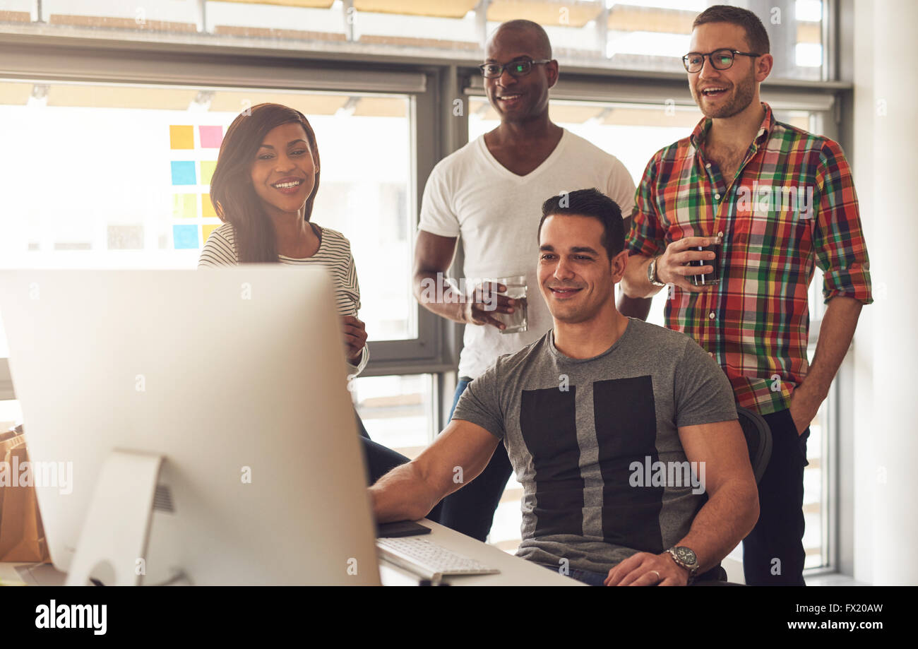 Bel ensemble de noirs, hispaniques et les jeunes adultes de race blanche à 24 smiling while looking at computer monitor in office Banque D'Images