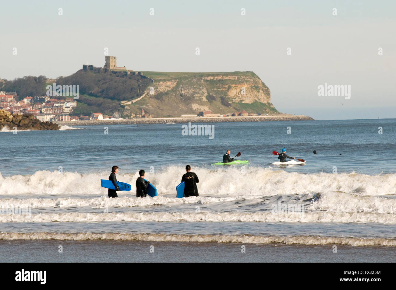 Cayton Bay, Scarborough, Royaume-Uni. 10 avril, 2016. Beau temps à Scarborough ; personnes surfant sur la mer du Nord ; à Cayton Bay ; le château de Scarborough en arrière-plan ; histoire de temps chaud et ensoleillé soleil anormalement anormalement histoires Crédit : picturesbyrob/Alamy Live News Banque D'Images