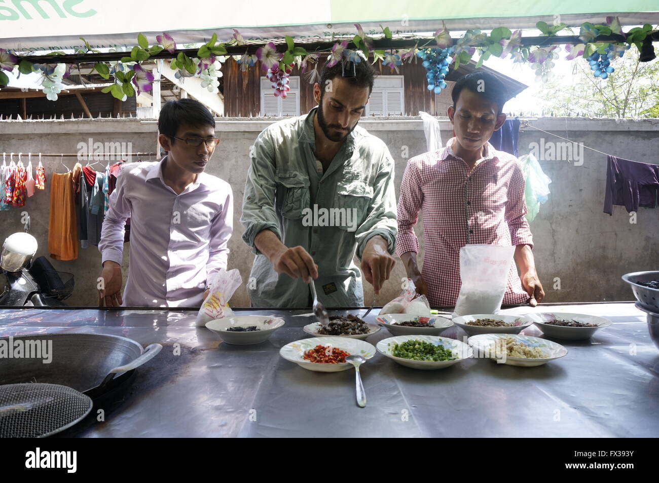 Nathan Thompson (C), le chef Sokha (R) et d'un interprète préparer les grillons à Phnom Penh, Cambodge, août 2015. Les experts disent que les insectes sont nutritifs et délicieux. Photo : Nathan Thompson/dpa Banque D'Images