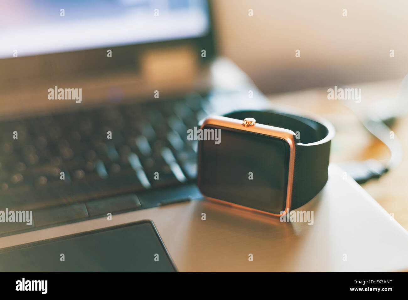 Montre-bracelet à puce moderne portant sur un ordinateur portable. La nouvelle technologie qui vous permet de rester toujours connecté à l'internet et des médias. Ne manquez jamais un message. La décoloration des couleurs du film Banque D'Images